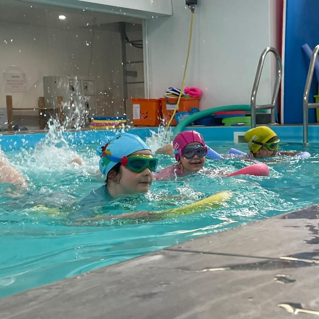 Older children practising swimming with floats