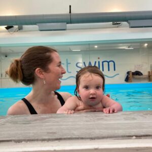 Baby with a parent at the edge of the First Swim pool