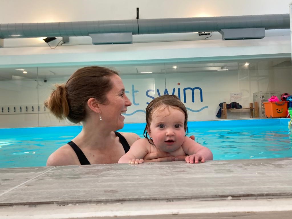 Baby with a parent at the edge of the First Swim pool