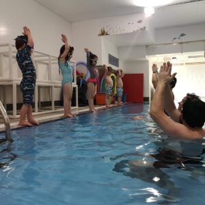 Toddlers practising poolside skills with their teacher