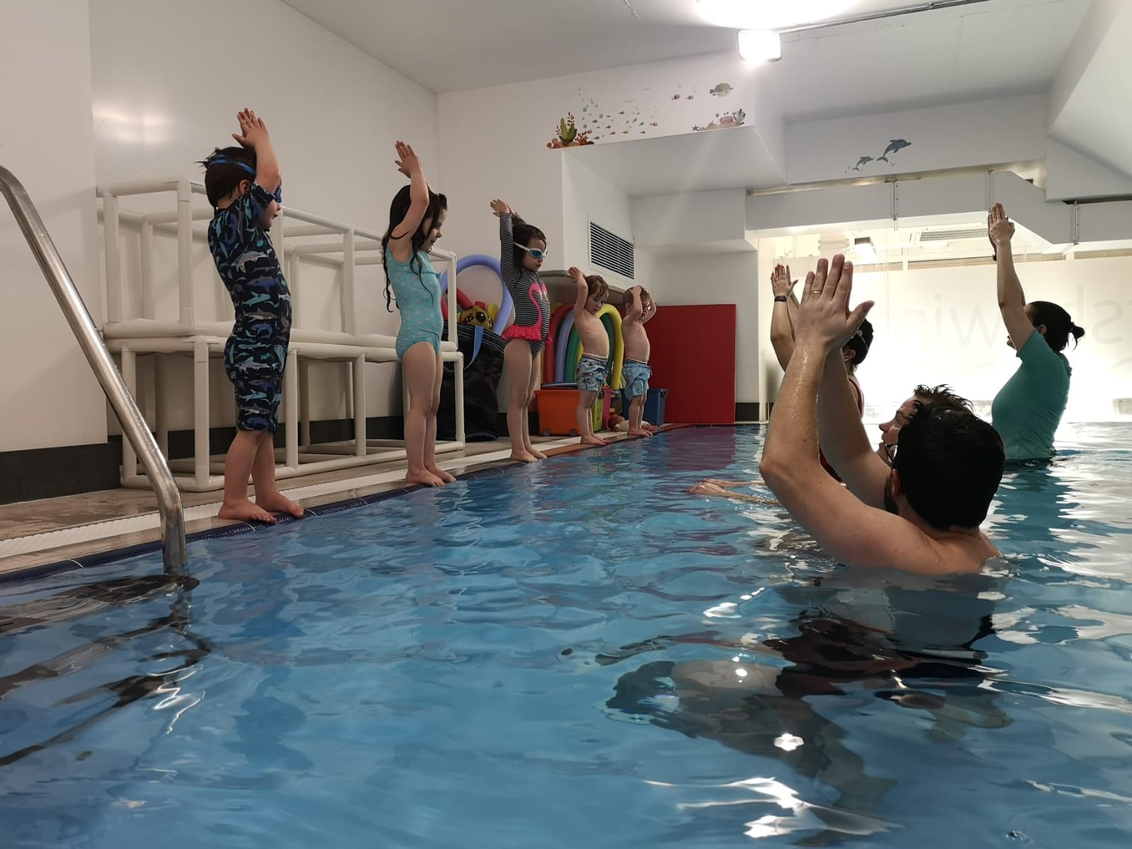 Toddlers practising poolside skills with their teacher