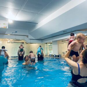 Toddler supported by an adult during a swimming lesson