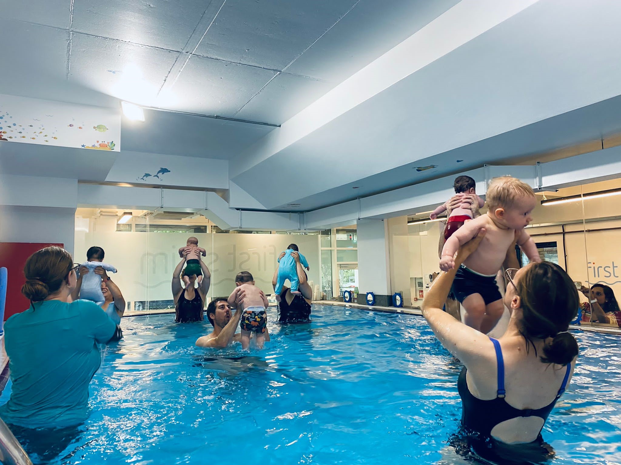 Toddler supported by an adult during a swimming lesson