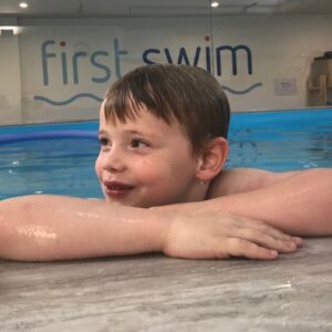Older child resting at the side of the First Swim pool