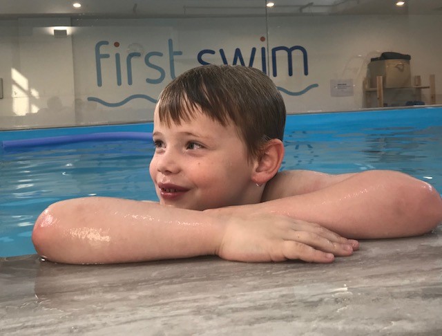 Older child resting at the side of the First Swim pool